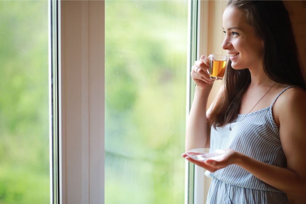 A photo of a woman drinking tea made with her best tea kettle.