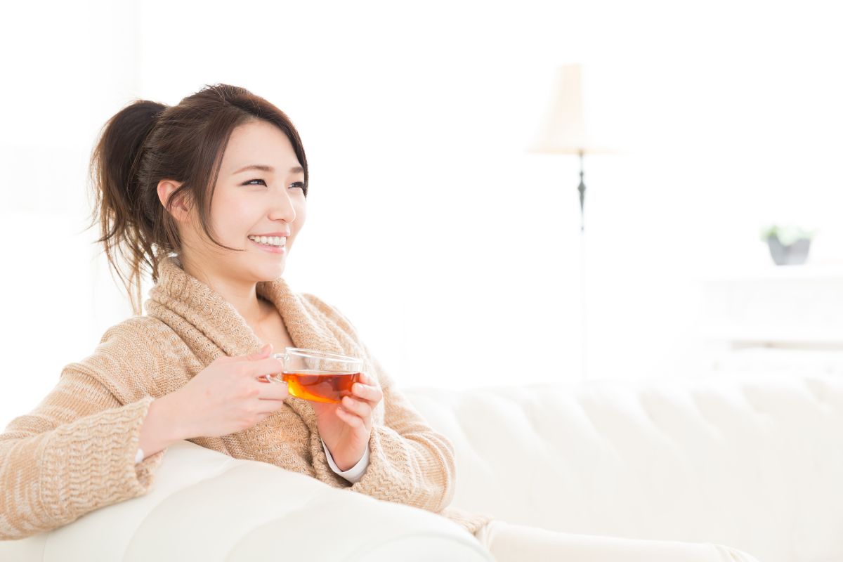 A photo of a woman drinking tea made with her non-toxic tea kettle.