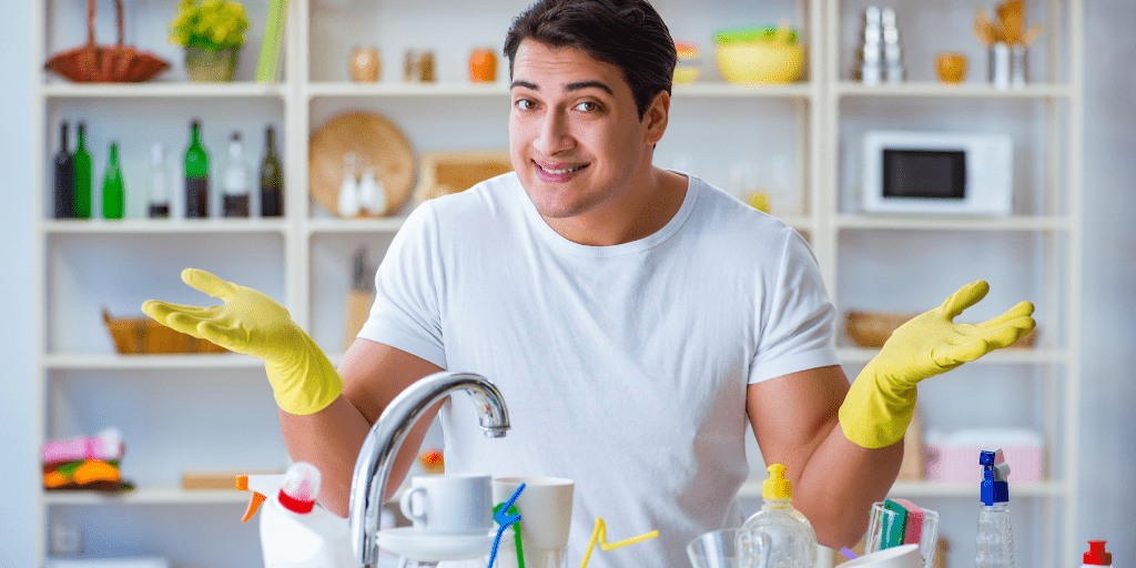A phot of a man wearing rubber gloves and standing by the sink.