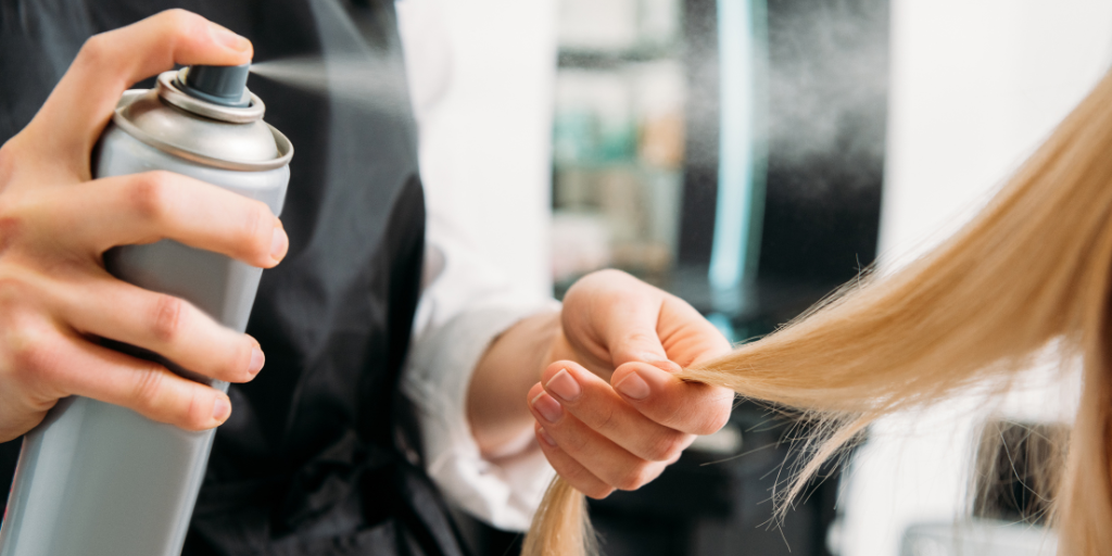 A photo of a woman using a hair spray with cyclopentasiloxane.