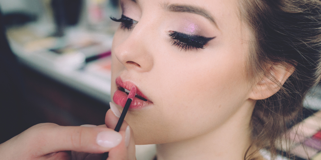 A photo of a woman applying lip makeup.
