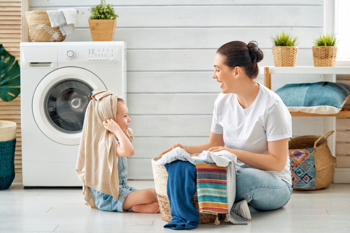 A photo of mom and kid doing laundry with a products with potentially non-toxic laundry detergent ingredients.